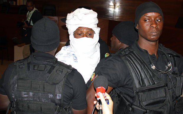 Security personnel surround former Chadian dictator Hissene Habre inside the court in Dakar, Senegal, Monday, July 20, 2015. The trial of former Chadian dictator Hissene Habre, accused of overseeing the deaths of thousands, had a chaotic beginning Monday as security forces ushered the ex-leader into and then out of the Senegal courtroom amid protests by his supporters.(AP Photo/Sophiane Bengeloun)